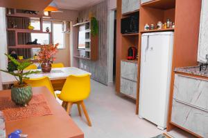 a kitchen with a table and a white refrigerator at Apartamento sofisticado, confortável e bem equipado - Loft Felau in Cuiabá