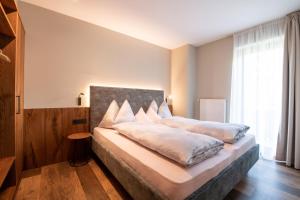 1 dormitorio con 1 cama grande con almohadas blancas en Apartments Karbon, en Castelrotto