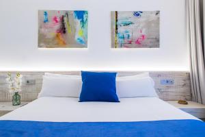 une chambre avec un lit bleu et blanc avec deux tableaux dans l'établissement Hotel Vacanzy Urban Boutique Adults Only, à Corralejo