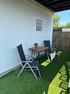a patio with two chairs and a table on grass at LiMo Apartman in Fonyód