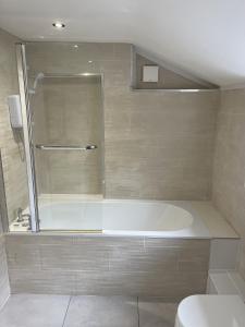 a bathroom with a bath tub and a toilet at Adanhouse-stockland spacious 5 bedroom house sleeps 12 private garden in Cardiff
