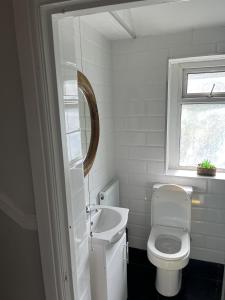a white bathroom with a toilet and a sink at Adanhouse-stockland spacious 5 bedroom house sleeps 12 private garden in Cardiff