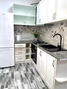 una cocina con armarios blancos y fregadero en Cosy place to stay, en Timisoara