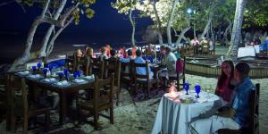 a group of people sitting at tables on the beach at night at Your Home Away From Home in San Felipe de Puerto Plata