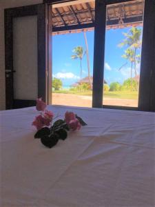 Una cama blanca con flores rosas encima. en Casa 110m2 beira mar - 2 quartos - Condomínio Bouganville Piscina 25m e ampla área verde -S Miguel do Gostoso, en Touros