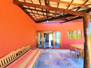 una habitación con una pared de color naranja con un banco y una mesa en Casa 110m2 beira mar - 2 quartos - Condomínio Bouganville Piscina 25m e ampla área verde -S Miguel do Gostoso, en Touros