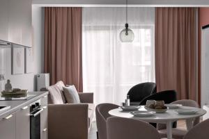 a living room with a table and chairs and a kitchen at APARTIO ROOMS Gliwice in Gliwice