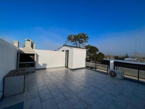 a balcony of a white building with a patio at Monoambiente vista lateral en Pinamar in Pinamar