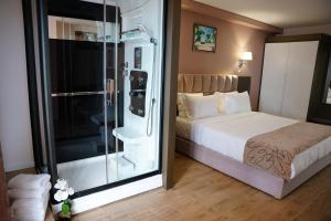 a bedroom with a bed and a glass shower at Doanesia Premium Hotel & Spa in Tirana