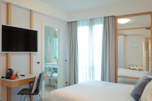 a hotel room with a bed and a desk and a television at Hotel Luna in Marina di Massa