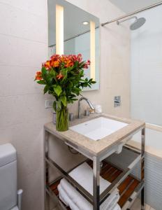 a bathroom with a sink with a vase of flowers at Luxurious 1BD Apartment Steps from Times Square in New York