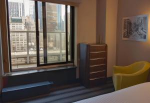 a bedroom with a bed and a window and a yellow chair at Hotel Edison Times Square in New York