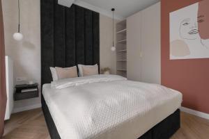 a bedroom with a white bed with a black headboard at APARTIO ROOMS Gliwice in Gliwice