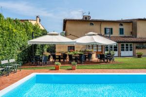 an outdoor patio with a pool and umbrellas at Villa Maria - b&b di Charme in Vicopisano