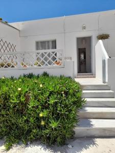 a white house with stairs and a bush at Zolfo Antico Beach Apartment Perissa in Perissa