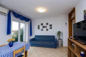 a living room with a blue couch and a tv at Apartments Marlen in Mali Lošinj