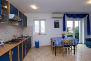 a kitchen with a table and a kitchen with blue cabinets at Apartments Marlen in Mali Lošinj