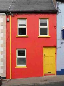 a red building with a yellow door and windows at Central Sligo Townhouse in Sligo