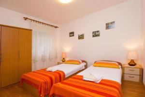 a bedroom with two beds with orange and white sheets at Apartments Marlen in Mali Lošinj