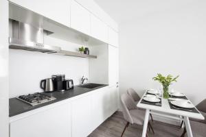 a kitchen with white cabinets and a white table and chairs at Cozy 2BD near Times Square with Doorman and Gym in New York