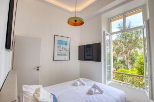 a white bedroom with a bed and a window at LimeSTAY - The Cannois T2 Modern WIFI in Cannes