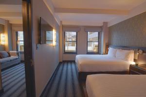a hotel room with two beds and a couch at Hotel Edison Times Square in New York