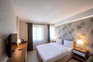 una camera d'albergo con un grande letto e una TV di MELL City Hotel Trabzon a Trabzon