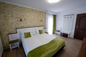 a bedroom with a large bed with green pillows at Evergreen Chalet in Avrig