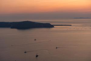 a group of boats in the water at sunset at Serendipity Cliffside Villa & Suites in Imerovigli