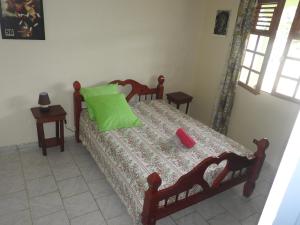 a bedroom with a bed with a green pillow on it at Vacances Antilles in La Trinité