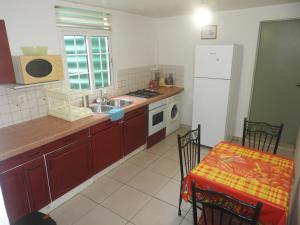 a kitchen with a sink and a table and a refrigerator at Vacances Antilles in La Trinité