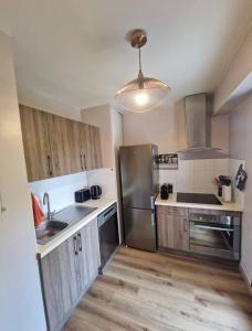 uma cozinha com electrodomésticos em aço inoxidável e pisos em madeira em Cagnes sur Mer-Spacieux 2 pièces em Cagnes-sur-Mer
