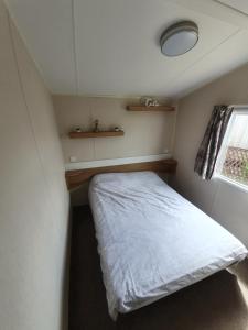 a small bedroom with a bed and a window at Fantasy Island King Fisher 8Berth 401 in Ingoldmells