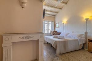 a white bedroom with a bed and a fireplace at Caelum Hyblae in Ragusa