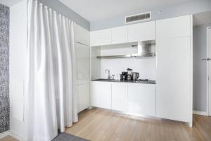 a white kitchen with white cabinets and a curtain at Stylish 2BD with Washer and Dryer near Times Square in New York