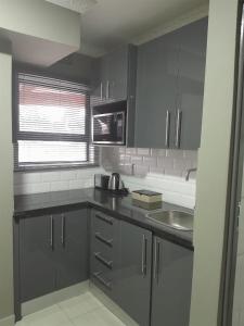 a kitchen with gray cabinets and a sink at Intuthuzelo on Bramleigh in East London