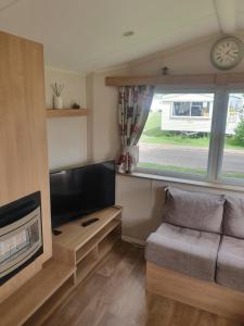 a living room with a couch and a tv and a window at Fantasy Island King Fisher 8Berth 401 in Ingoldmells