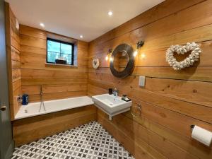 baño con paredes de madera, lavabo y bañera en The Old Stables, en Salisbury