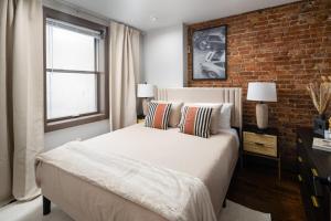 1 dormitorio con cama y pared de ladrillo en Modern Luxury 3BD and 2BA in the Heart of East Village en Nueva York