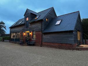 une maison avec un toit noir et un bâtiment en briques dans l'établissement The Old Stables, à Salisbury