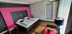1 dormitorio con cama rosa y mesa en Vila Privilege Felix en Baile Felix