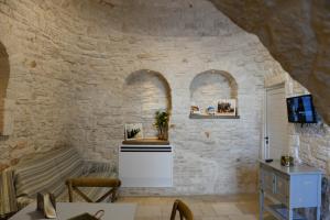 una camera con un muro in pietra con due archi di Trullo A Casedd ad Alberobello