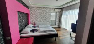 a bedroom with a bed with a pink wall at Vila Privilege Felix in Baile Felix