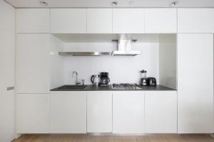 a white kitchen with white cabinets and a sink at Modern 2BD in Midtown with Washer and Dryer in-unit in New York