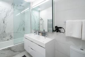 a white bathroom with a sink and a mirror at Chic and Spacious 2BD Apt with washer and dryer in unit in New York