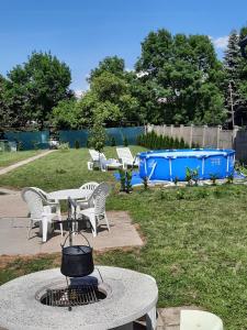 a fire pit in a yard with chairs and a grill at Alexander apartman in Gyula