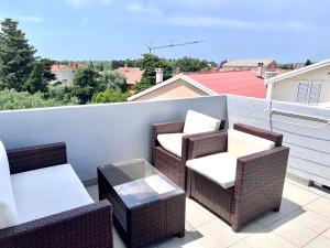 three wicker chairs and a table on a balcony at Apartments Ana & Ita in Novalja