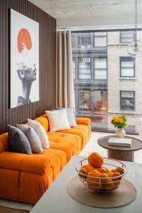 an orange couch in a living room with a bowl of oranges at Stunning 2BD Penthouse in Chelsea w Washer and Dryer in New York