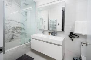 a white bathroom with a sink and a shower at Stunning 2BD Penthouse in Chelsea w Washer and Dryer in New York