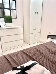 a white bedroom with a bed and a dresser at Apartments Ana & Ita in Novalja
